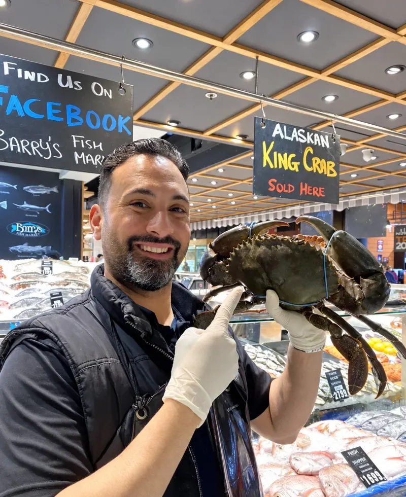 Barry holding up a live mud crab at the counter